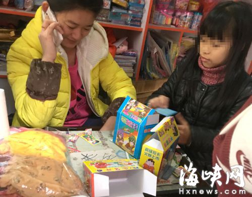 小女孩（右一）正在购买“彩票”，一旁是店老板