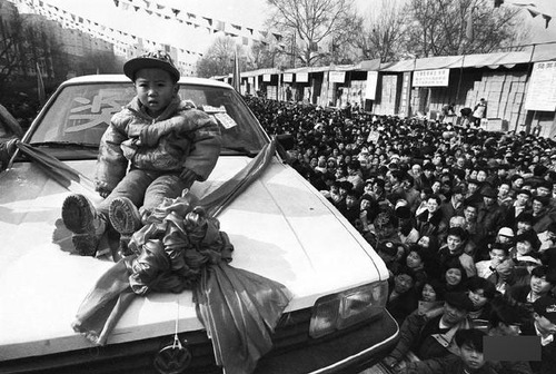 1997年，在北京街头的彩票开奖现场，四川来京务工人员伍富贞家3岁的孩子幸运中得一辆轿车。上世纪九十年代，即开型彩票风靡一时，在“意外之财”的诱惑下，人人都想一试手气，开奖现场人山人海。胡金喜 摄