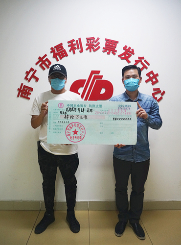 南宁市福彩中心工作人员为李先生（左）颁奖