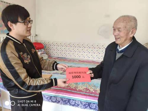 工作人员（左）将1000元福彩帮扶慰问金送到老人手里
